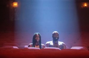 Un homme et une femme sont assis nus dans une salle de cinéma déserte, scène de la série Monsterland.