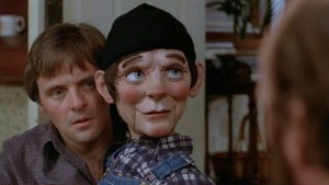 Anthony Hopkins derrière sa marionnette, tous deux ont l'air sérieux, ils regardent un homme dont on ne voit qu'une amorce de visage à droite de l'image ; plan du film Magic.