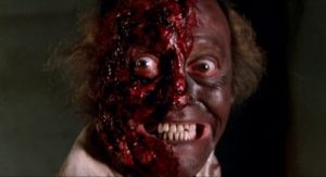 Gros plan sur le visage d'un zombie du film Virus Cannibale, à motié décharné.
