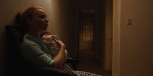 Dans un couloir sombre de pavillon, une mère inquiète sert contre elle son bébé dans la série Servant saison 2.
