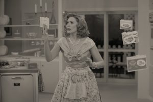 Vêtue en femme de ménage des années 50, Wanda Maximoff tient dans sa main une petite carte, tandis que d'autres cartes flottent dans l'air à côté d'elle ; plan en noir et blanc de la série WandaVision.