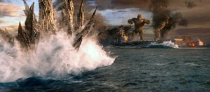 Au premier plan, les éclailles dorsales de ce qui semble être un dinosaure fendent la mer ; au second plan, Kong sur un bateau qui coule ; scène du film Godzilla vs Kong.