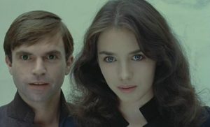 Sam Neill et Isabelle Adjani côte à côte regardent devant avec un regard étrange, malicieux et malsain.