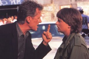 Plan rapproché-épaule sur James Woods qui dispute Michael J. Fox, le doigt levé vers son visage dans le film La manière forte.