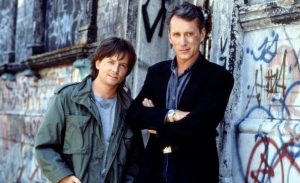 James Woods et Michael J. Fox posent avec le sourire devant un mur de graffiti dans le film La manière forte.