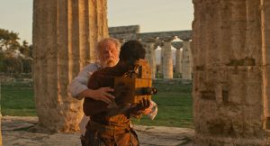Un jeune homme noir est en train de filmer avec une vieille caméra, tandis qu'un vieil homme derrière lui lui place les mains sur l'appareil ; scène du film Last Words.