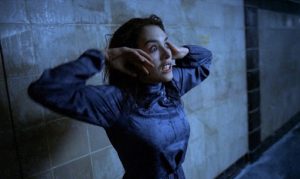 Isabelle Adjani en transe, les yeux exorbités, contre un mur de pierre dans le film Possession.