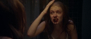 Amanda Fuller se regarde dans le miroir, ses lèvres sont blessées, elle a l'air d'un monstre ; scène du film Starry Eyes.