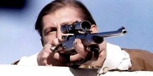 Plan rapproché-épaule sur un sniper, l'œil derrière son fusil, issu du film Le conseiller.