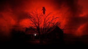 Sous un angoissant ciel rouge, se dessine un arbre et une petite maison plongée dans l'obscurité ; plan issu du film The Dark and the Wicked.