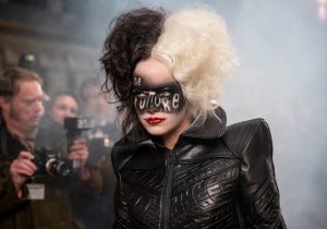 Cruella défile sous les yeux des photographes, elle porte un manteau en cuir et sur son visage est peint un liseret noir sur lequel on peut lire Future.