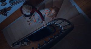 Plan en plongée sur les escaliers de la maison de Messe Basse réalisé par Baptiste Drapeau : Jacqueline Bisset est debout, se tient à la rambarde tandis qu'Alice Isaaz est allongée sur les marches à ses pieds.