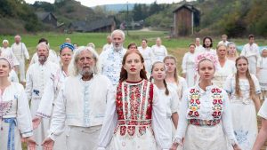 La communauté du film Midsommar, en tenue traditionnelle blanche, se tient main dans la main, jeunes et vieux, plan pour illustrer notre entretien avec Marc Olry.