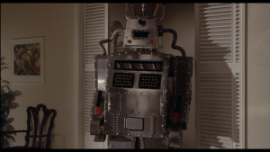 Le robot tueur kitsch et très 70's - qui ressemble à plusieurs boîtes d'acier empilées les unes sur les autres - se tient debout dans un salon du film Supersonic Man.
