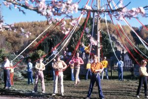Plusieurs hommes et femmes sont attachés par des cordes colorées à un poteau en bois dans le film The Wicker Man.