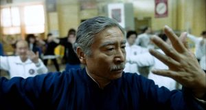 Plan rapproché-épaule sur un maître de tai-chi en plein cours issu du film Pushing Hands de Ang Lee. 