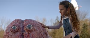 Dans le film Psycho Goreman, la petite Mimi caresse un gentil monstre qui a l'air d'un cerveau avec juste deux grand yeux ronds.