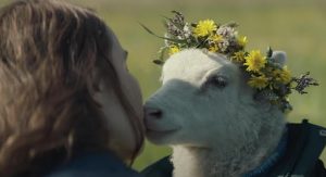 Une femme pose sa joue contre le museau d'une brebis portant une couronne de fleurs sur le crâne ; scène du film Lamb.