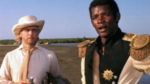 Marlon Brando et un esclave noir vêtu en costume militaire de l'époque, avec médaille et épaulettes dorées, regardent l'horizon dans le film Queimada.