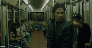 Le policier Sysoy dans une rame de métro où tout le monde est assis sauf lui, l'air inquiet et alerte dans le film On the job 2.