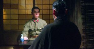 Dans un salon japonais, Onoda jeune militaire est assis face à son maître, en tenue traditionnelle et que nous ne voyons que de dos ; plan issu du film de Arthur Harari Onoda - 10 000 nuits dans la jungle.