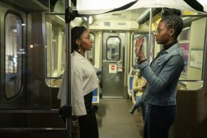 Deux jeunes femmes parlent face à face, debout dans un métro quasi-vide ; scène du film Candyman.