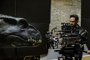 Juan Antonio Bayona en tournage, cadre avec sa caméra une tête de dinosaure carnivore.