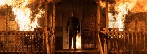 Michael Myers sur le perron d'une maison en flammes dans le film Halloween Kills.