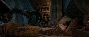 Une patte de dinosaure s'approche d'une petite fille terrorisée, dans son lit d'enfant ; scène du film Jurassic World : Fallen Kingdom de Juan Antonio Bayona.