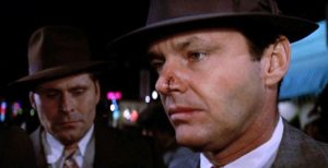 Plan rapproché-épaule sur le visage de Jack Nicholson le regard abattu contemple le corps mort de son amoureuse, dans les rues de Chinatown, le film analysé dans le livre The Big Goodbye.
