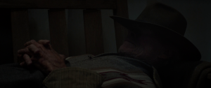 Clint Eastwood fait une sieste allongé sur le canapé, le chapeau baissé sur le nez dans le film Cry Macho.