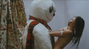 Une femme sous la douche tente de se débattre, les bras bloqués sous les aisselles d'un bonhomme de neige ; plan issu du film Jack Frost.