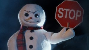 Un bonhomme de neige au sourire mesquin tient un panneau stop dans le film Jack Frost.