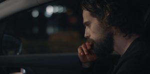 Léo pensif, assis sur le siège conducteur de sa voiture ; scène de nuit du film Hors du monde de Marc Fouchard.