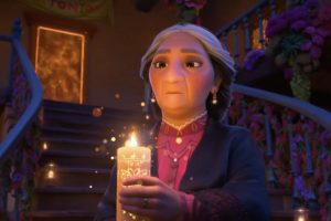 Une grand-mère aux pieds de grands escaliers, tient une bougie dans sa main dont elle regarde la flamme d'un air pensif ; scène du film Encanto, la fantastique famille Madrigal pour notre article sur Disney 2021.
