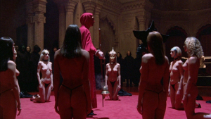 Scène de rituel du film Eyes Wide Shut où 7 femmes sont agenouillées nues autour d'un homme portant une toge rouge.