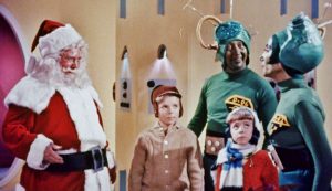 Le Père Noël tout sourire fait face à deux enfants et deux Martiens dans le film Le Père Noël contre les martiens.