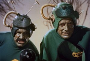 Deux Martiens - deux hommes en costume verts dont le visage humain est à peine peint en vert - montre un visage menaçant à leur victime hors-champ dans le film le Père Noël contre les martiens.