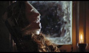 Le visage d'une femme étouffée dans un sac, assise près d'une fenêtre, vue de profil et de nuit dans le film Black Christmas (1974).