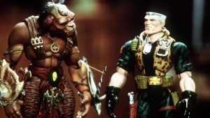 Les deux jouets animés, le soldat Chip Hazard et le Chien guerrier Archer parlent, debout l'un à côté de l'autre dans le film Small Soldiers.
