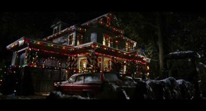 Plan d'ensemble nocturne sur la grande maison du film Black Christmas (2006) copieusement décorée en guirlande de Noël.