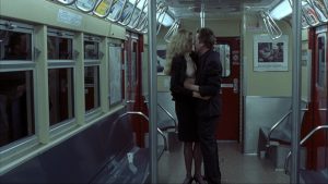 Un homme et une femme prêts à faire l'amour - la femme à son chemisier ouvert - debout en plein milieu d'une rame de métro déserte dans le film The King of New-York.