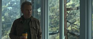 Plan du documentaire Michael Cimino un mirage américain dans lequel le cinéaste est chez lui, gobelet de café à la main, devant une baie vitrée.