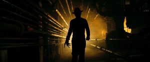 La silhouette de Freddy Krueger se dessine en clair-obscur, dans un sous-sol d'usine pour notre article sur le slasher 2022.