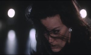 Gros plan nocturne sur le visage déterminé de Florinda Bolkan, les cheveux en mouvement devant ses yeux dans le film Exécutions (1969).