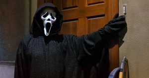 Le Ghostface de Scream bloque une porte avec son bras, malicieusement ; plan issu du film de Wes Craven pour notre article sur le slasher 2022.