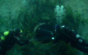Deux plongeurs sous l'eau abordent ce qui semble être une vieille évacuation non-utilisée ; plan issu du film The deep house de Alexandre Bustillo et Julien Maury.