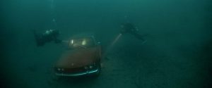 Les deux plongeurs du film The Deep House, réalisé par Alexandre Bustillo et Julien Maury, atteignent une voiture immergée qu'ils inspectent avec des lampes-torche.
