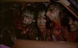 Des possédés, à l'air de zombies, se collent au pare-brise d'une voiture, affamés; scène de nuit issue du film Démons.