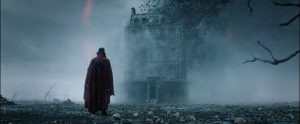 Plan d'ensemble sur un vieux manoir plongé dans un brouillard surnaturel, Docteur Strange, vu de dos, l'observe ; scène du film de Sam Raimi.
